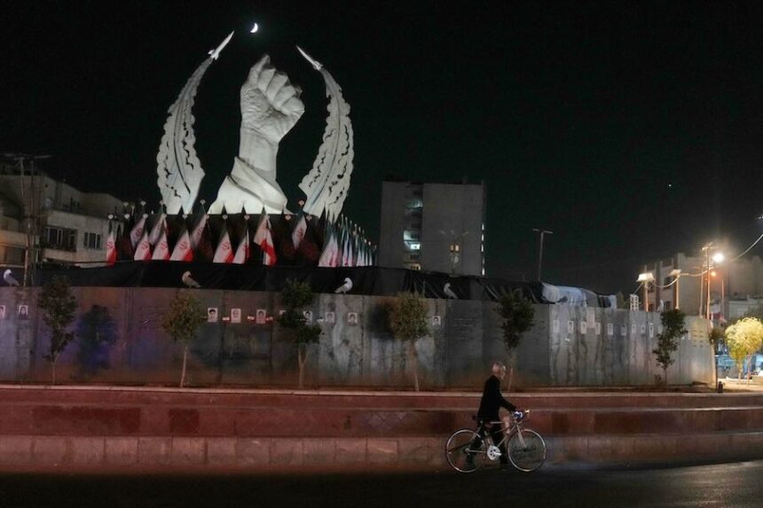 A man carries his bicycle in front of a monument depicting the clenched fist of the late Iranian Supreme Leader Ayatollah Ali Khamenei, who was killed in the U.S. and Israel strike on Feb. 28, in Islamic Revolution Square in Tehran, Sunday, July 19, 2026.