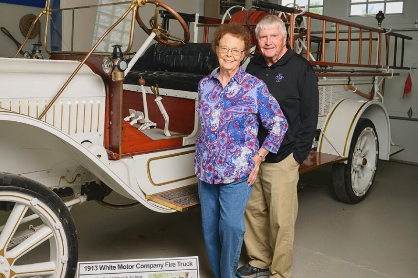 Judy and Mark Kirkham standing beside a white automobile wagon with Mark hugging close to his wife and both smiling together. | Courtesy photo.