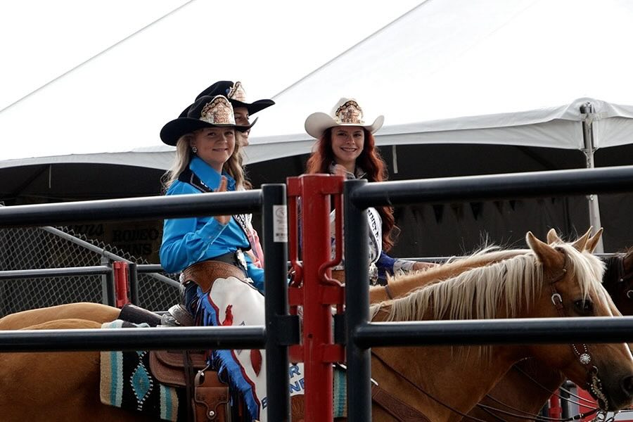 War Bonnet Rodeo Royalty of 2026 rest on their horses, waving and smiling, at a press event at Sandy Downs, Wednesday, in Idaho Falls. War Bonnet Princess Edie Barnes is at the front.