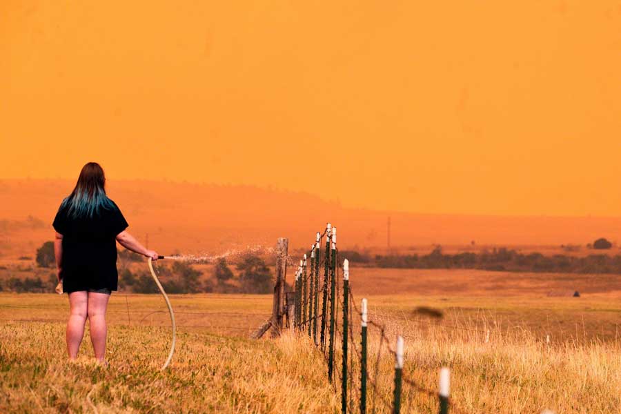 A woman uses a hose to dampen grass around the Mountain Shadows Mobile Estates mobile home park in Beulah, Colorado, on Monday, June 29, 2026.