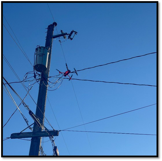 Bright orange drone aerially inspects power pole hardware. | Photo Courtesy of MJ Inspection