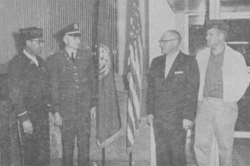 Adhering to policy, the Rigby branch of the Idaho First National Bank recently gave a permanent place of honor to the American and Idaho state flags. Participating in the ceremony were left to right, Leigh Nielsen, Lt. James Hill, Mayor A.B. Eckersell and Rees Johnson. Caption dated May 3, 1962.