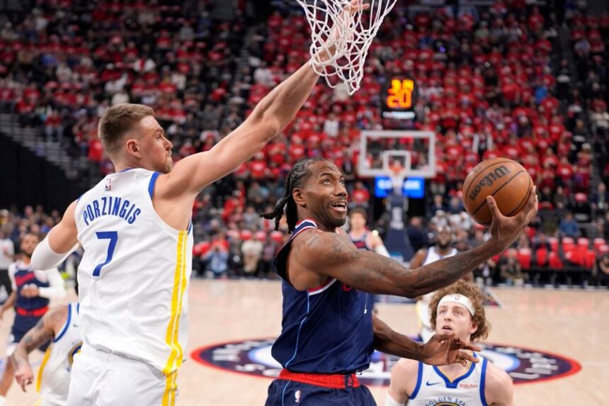 FILE - LA Clippers forward Kawhi Leonard, center, shoots as Golden State Warriors center Kristaps Porzingis defends during the first half of an NBA play-in tournament basketball game Wednesday, April 15, 2026, in Inglewood, Calif. (AP Photo/Mark J. Terrill,File)