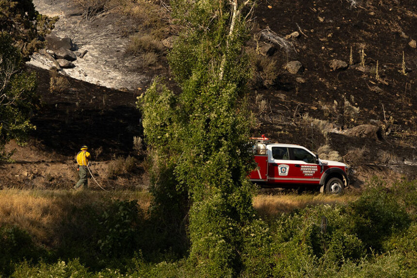 Fire crew from Bonneville County Fire District #1 spraying the edge of East Heise Road where the Big Rock Fire was held before the roadway. | Daniel V. Ramirez, EastIdahoNews.com