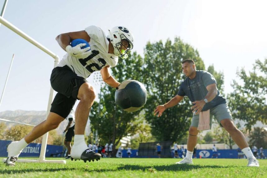 BYU running backs coach Harvey Unga, right, with running back Preston Rex runs drills during training camp, Tuesday, Aug. 25, 2026 in Provo, Utah. (Photo: Jaren Wilkey, BYU Photo)