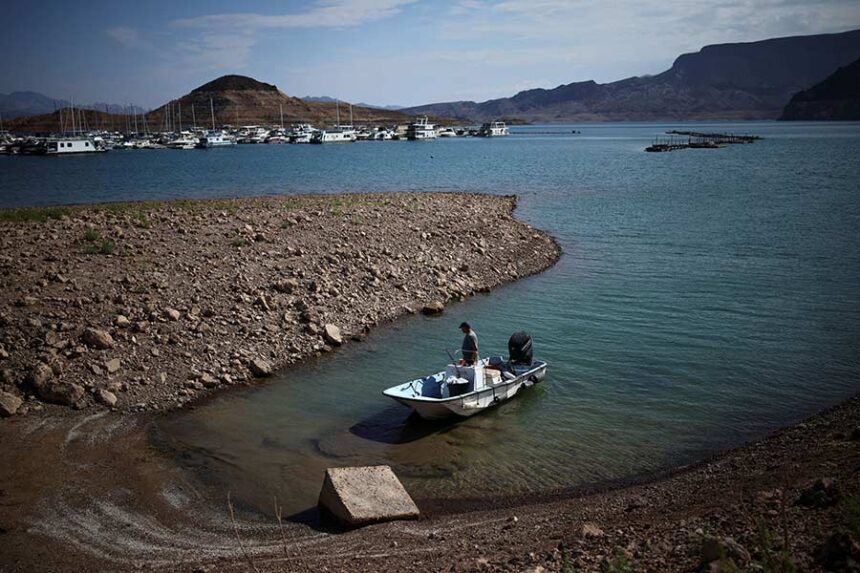 A man wades his boat into the receding shoreline of Lake Mead, the largest reservoir in the United States by water capacity, highlighting the long-term effects of drought and water demand on the Colorado River system, near Boulder City, Nevada, August 12. Mandatory Credit: Daniel Cole/Reuters via CNN Newsource