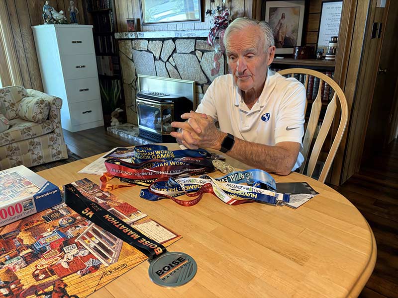 Noel Johnson at his home looking at his 5K medals. | Devin Bodkin, IdahoEdNews.org