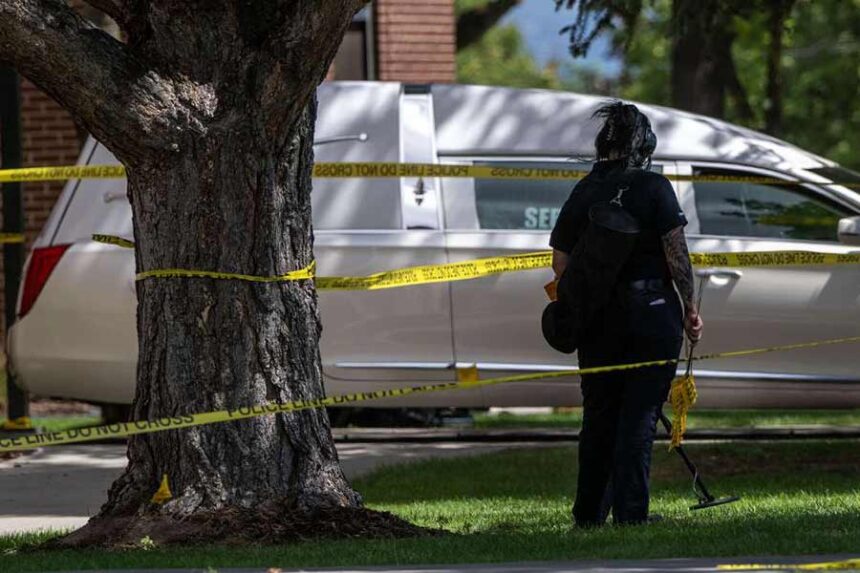 A member of the forensics unit uses a metal detector to search for evidence as police investigate a shooting that occurred in Kearns during a funeral on Monday.