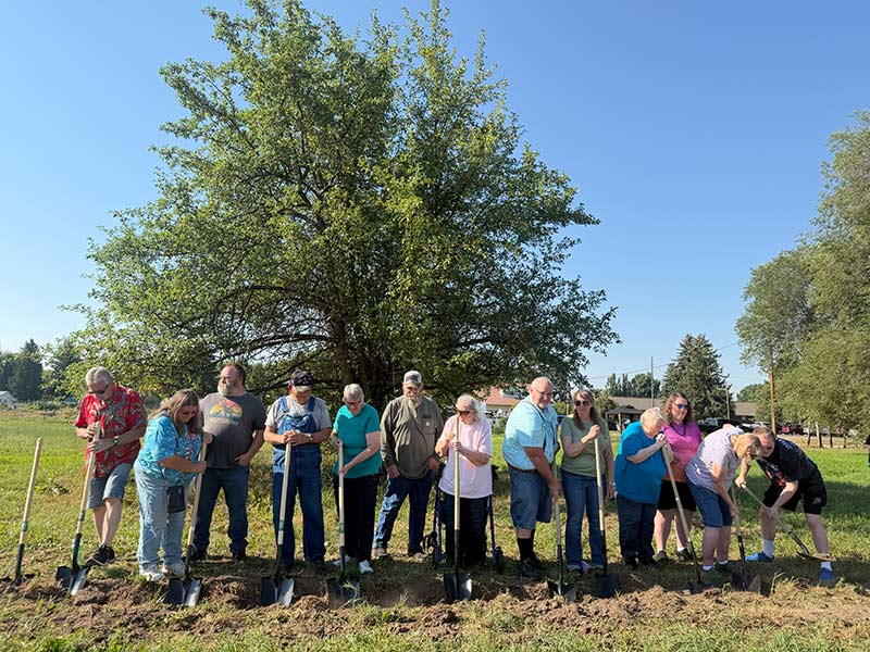 Crowd participates in a ceremonial turning of the soil during the groundbreaking of the new library in Menan on Saturday. | Courtesy James Zolman