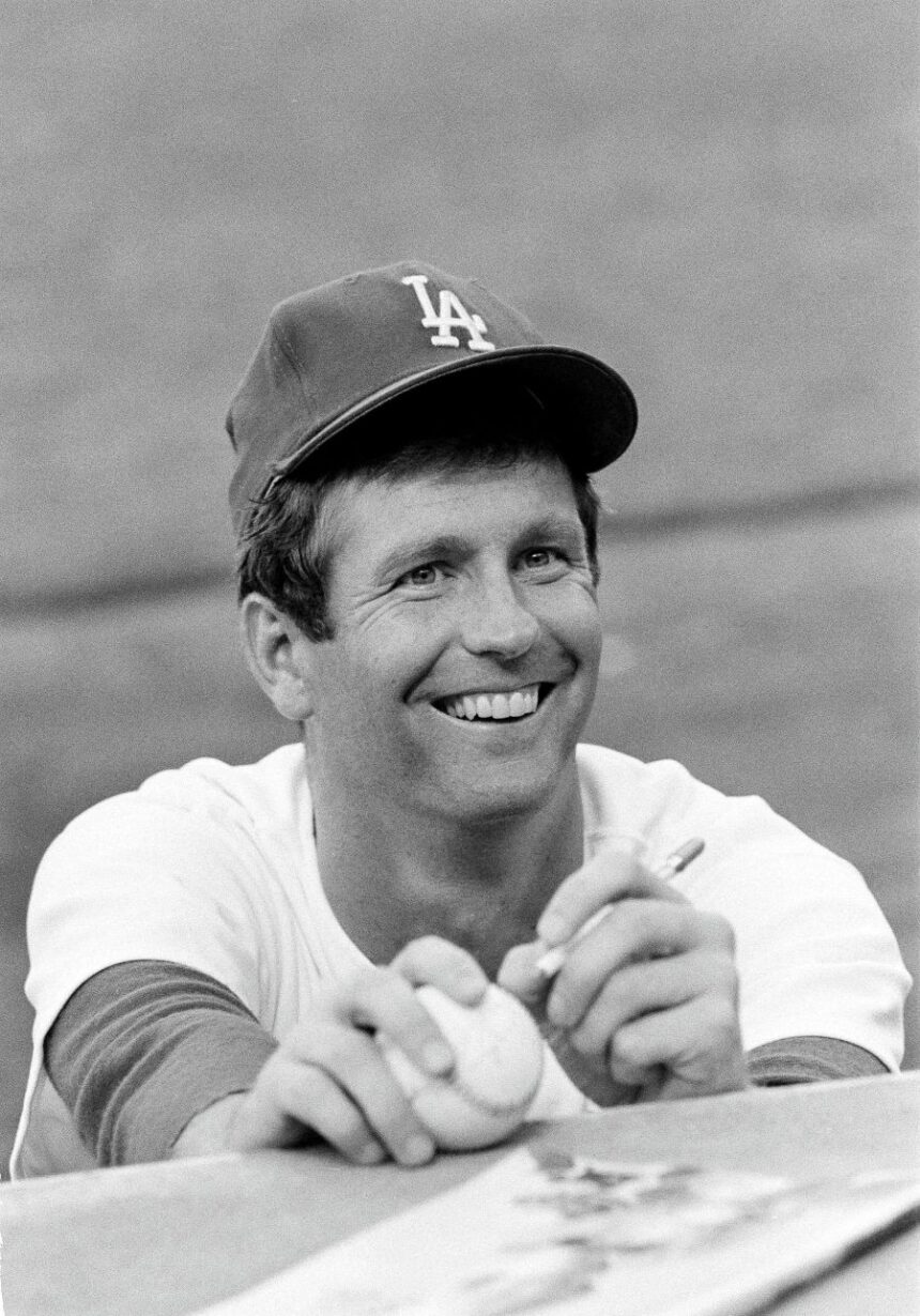 FILE - Lefthander Tommy John of the Los Angeles Dodgers signs an autograph before a game, Aug. 12, 1977. (AP Photo/Lennox McLendon, File)