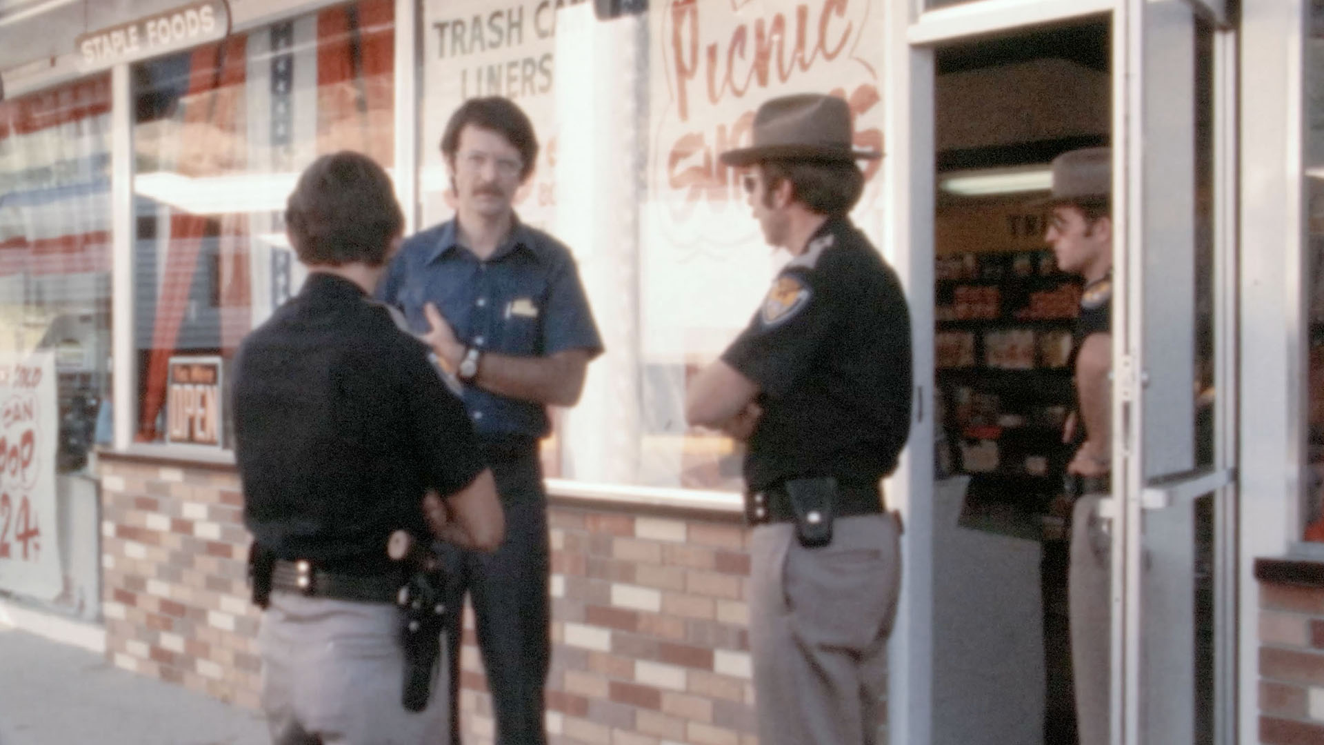 East Layton police officers David Anderson (right) and Gerald Burton (left) speak to KSL reporter Steve Schwartz on July 7, 1975, at the Fina gas station where Nancy Perry Baird was last seen three days prior.
