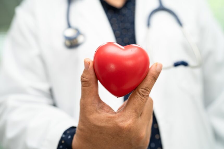 Doctor holding a red heart in hospital ward, healthy strong medical concept.