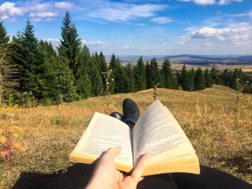 Enjoying a book outdoors on grassy hillside