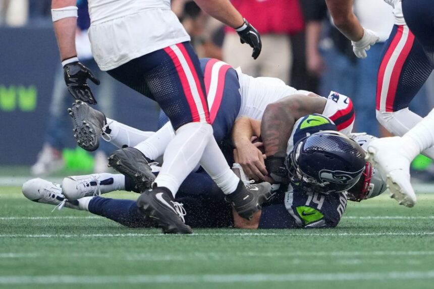 Seattle Seahawks quarterback Sam Darnold, (14) is sacked by New England Patriots linebacker Dre'mont Jones, behind, during the first half an NFL football game, Wednesday, Sept. 9, 2026, in Seattle. (AP Photo/Lindsey Wasson)