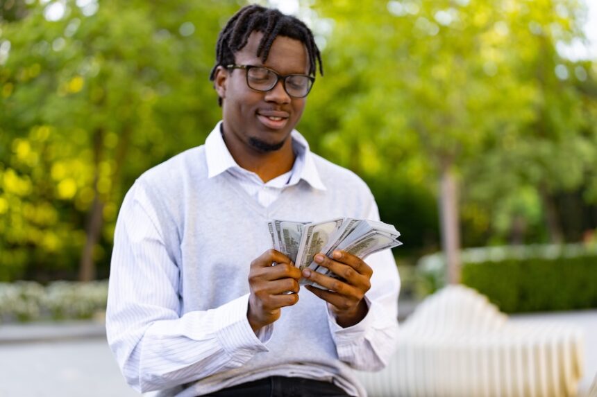 young man counting a fan of us dollar bills outdoo 2026 09 25 06 36 31 utc