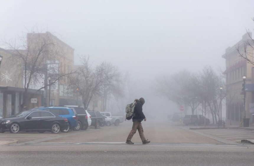 A man walks through downtown Nampa in heavy fog in this photo from 2023. Pedestrians must always walk along a sidewalk if one is available to use, according to Idaho Code.