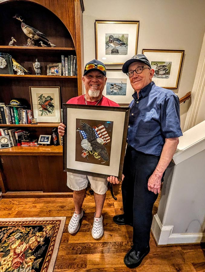 Mackay teacher Jess Johnson holds a framed print of an Earl Henry Sr. painting while posing with his son, Earl Henry Jr.