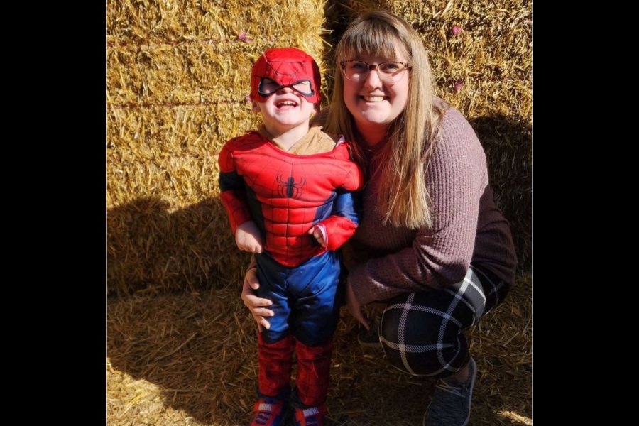 Braxtyn Peterson smiles while dressed in a Spider-Man costume beside his mother, Katelyn Spencer.