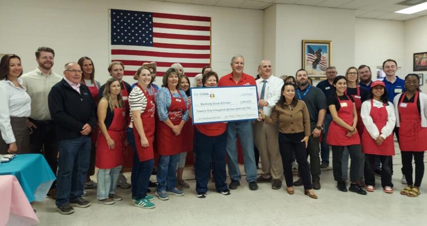 Co-owners of Rexburg Soup Kitchen, David and Margo Merrill, stand and smile amongst supporters and Grifols employees while holding the $25,000 national grant. | Michael Carruth, EastIdahoNews.com