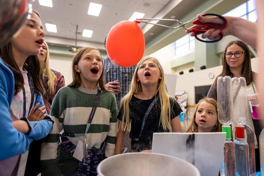 Children react as a volunteer uses tongs to hold a balloon inflated by dry ice vapor during Idaho National Laboratory's Family Nuclear Science Night on Oct. 24, 2025. | Courtesy INL