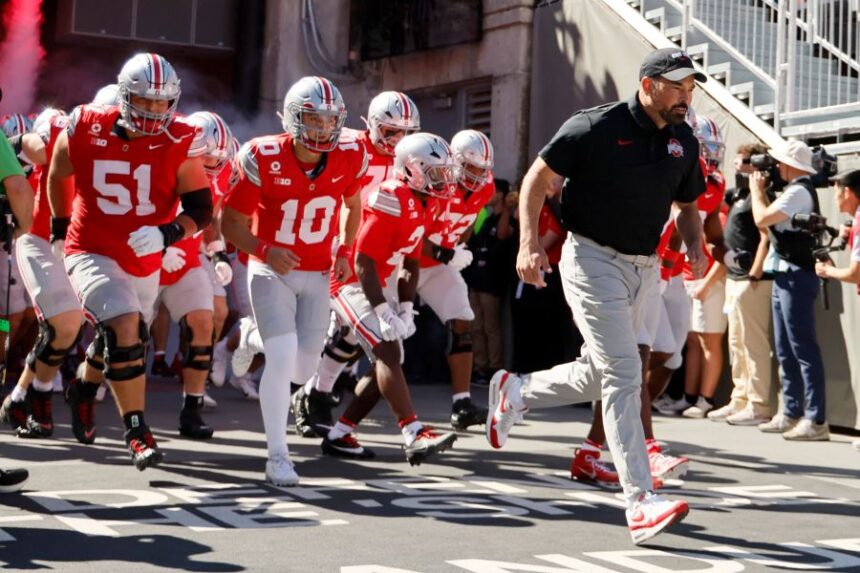 Ohio State head coach Ryan Day, right, leads the team onto the field for the start of an NCAA college football game against Illinois, Saturday, Sept. 26, 2026, in Columbus, Ohio. (AP Photo/Jay LaPrete)