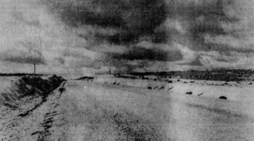 Stretching out into the Lost River desert solitude is the Twin Buttes Highway pictured above. Dedication rites for the vital new highway strip connecting the Upper Snake River Valley with central and west Idaho were held Monday. The highway, however, will not be so lonely after this week when crews complete application of a seal coat. Caption dated Oct. 8, 1951.