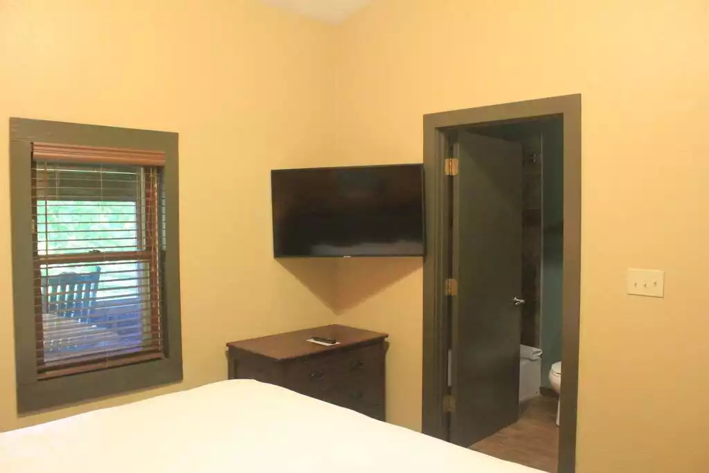 This bedroom looks out the private screened in porch. Rustic wood blinds fit nicely with the cabin decor. Dresser for storage and TV mounted on wall includes free cable. Door on right goes into master bathroom, which includes tub/shower combo. This bedroom looks out the private screened in porch. Rustic wood blinds fit nicely with the cabin decor. Dresser for storage and TV mounted on wall includes free cable. Door on right goes into master bathroom, which includes tub/shower combo. - Entire Cabin 3 Wisc Dells 3 Beds(2Bedrooms) 2Baths - Wisconsin Dells