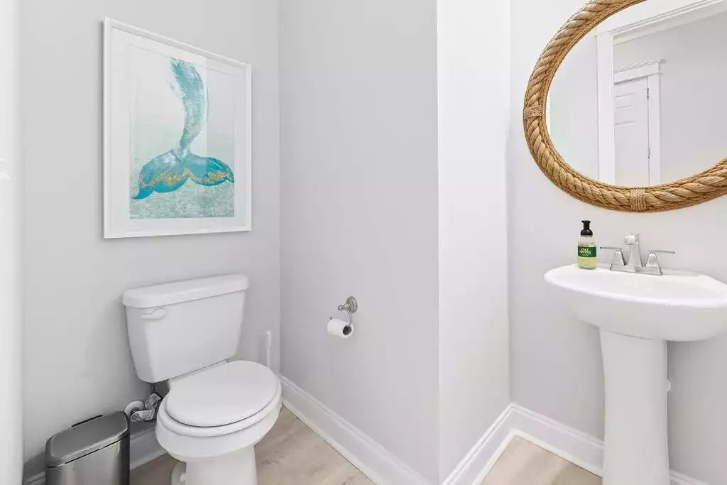 The downstairs powder bath is conveniently located in the center of the first floor and also near the garage entry. The nautical rope mirror and mermaid tail wall art add to the coastal chic theme of the home. The downstairs powder bath is conveniently located in the center of the first floor and also near the garage entry. The nautical rope mirror and mermaid tail wall art add to the coastal chic theme of the home. - Shipwrecked Beach House Orange Beach, Alabama - Orange Beach