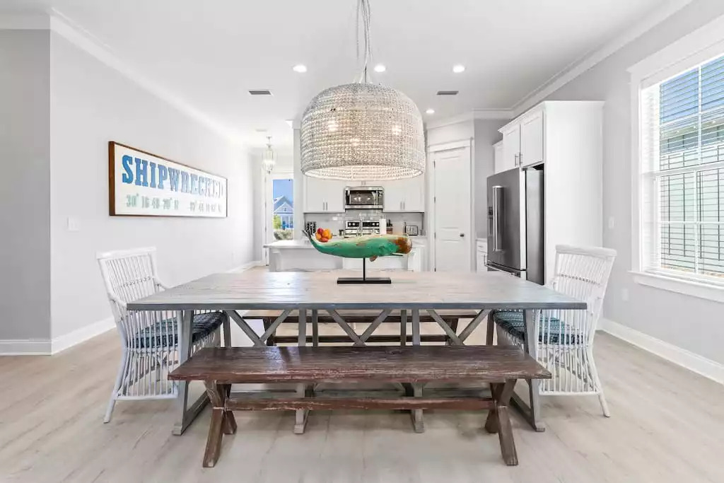 “Shipwrecked” provides dining space for up to 12 guests! The large coastal dining table with beach-vibe style chandelier and 3 dining swivel stools at the kitchen island provide a spacious seating area for meals. “Shipwrecked” provides dining space for up to 12 guests! The large coastal dining table with beach-vibe style chandelier and 3 dining swivel stools at the kitchen island provide a spacious seating area for meals. - Shipwrecked Beach House Orange Beach, Alabama - Orange Beach
