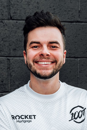 nadeshot smiling in front of brick wall with 100 Thieves jersey