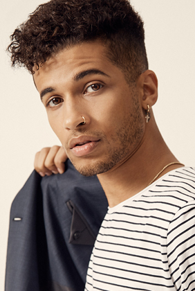 jordan fisher in striped tshirt holds navy jacket