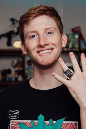 Scump smiling holidng up hand with ring