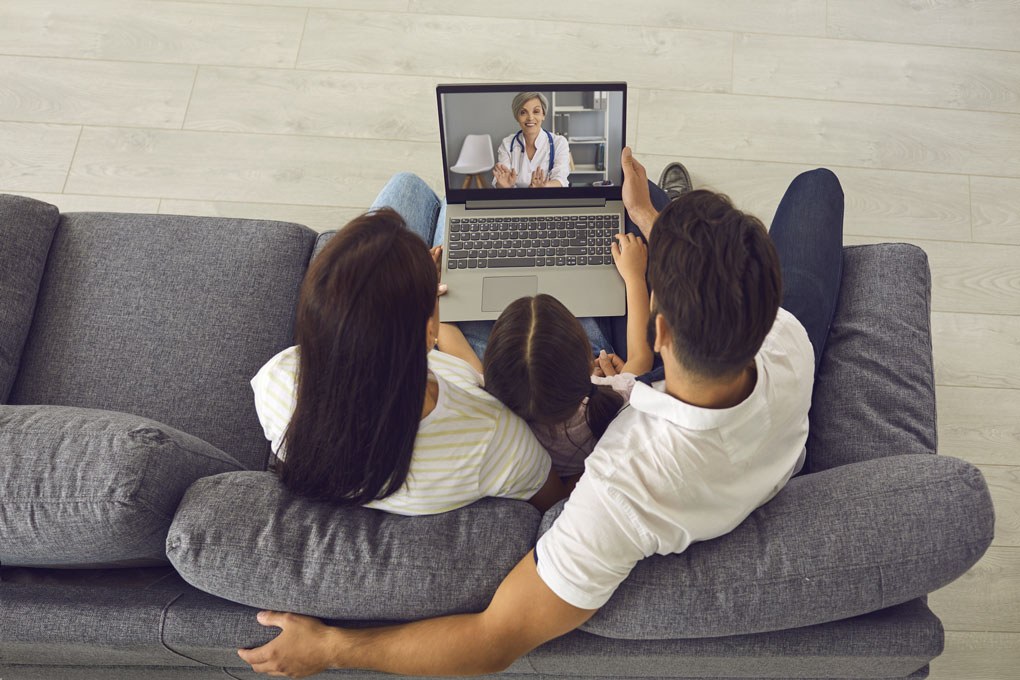 Family on sofa Telehealth meeting overhead