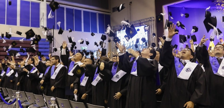 Alumnos graduándose y lanzando sus birretes,