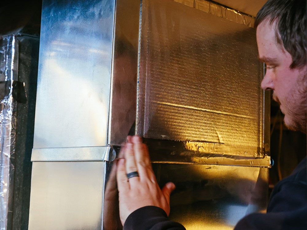 Air duct cleaning technician in Dillon resealing a furnace with tape after vacuuming