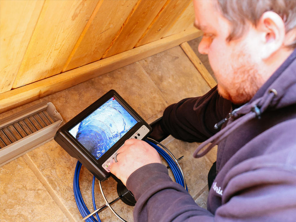 Alt text: Air duct cleaning technician in Dillon using a remote camera to inspect vents