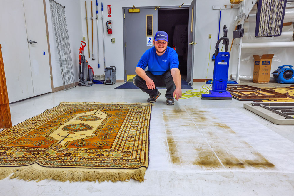 Whitehall area rug cleaning technician pointing at dust test spot to show buildup before cleaning