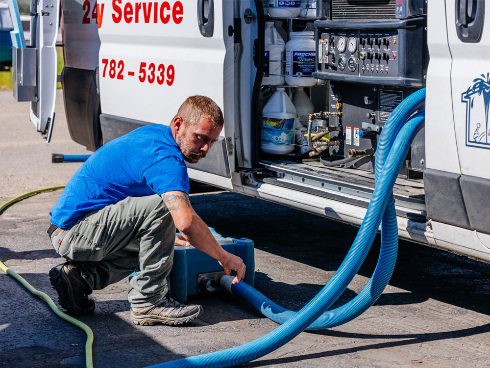 Technician adjusting carpet cleaning hoses connected to van during service in Whitehall MT