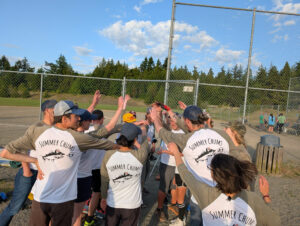 Group of softball players raising hands in a group cheer.