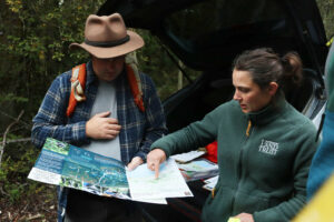 Man and woman studying maps in the woods.