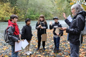 Four kids with adult on riverbank.