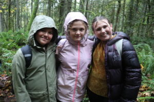 Three girls smiling in a forest.