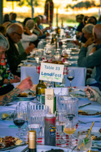 Row of dining tables with people eating and drinking under tent