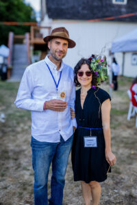 Man and woman posing for photo, woman wearing headpiece of leaves, flowers, and twigs