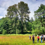 Group of people in field with trees beyond