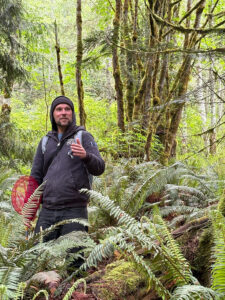 Man standing amongst ferns in a forest.