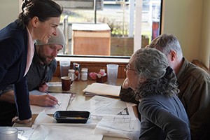 Photo of four people sitting at a table with drawings at a cafe.