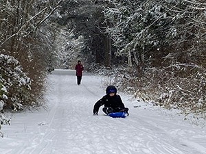 Photo of child sledding in the Quimper Wildlife Corridor. Photo by Robert Tognoli.