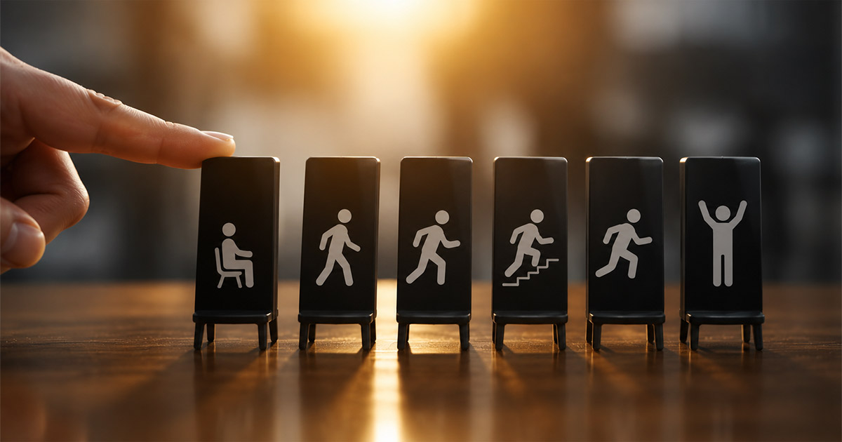 A hand tipping a row of black blocks with icons showing a person progressing from sitting to celebrating success, representing a domino effect in human motivation.