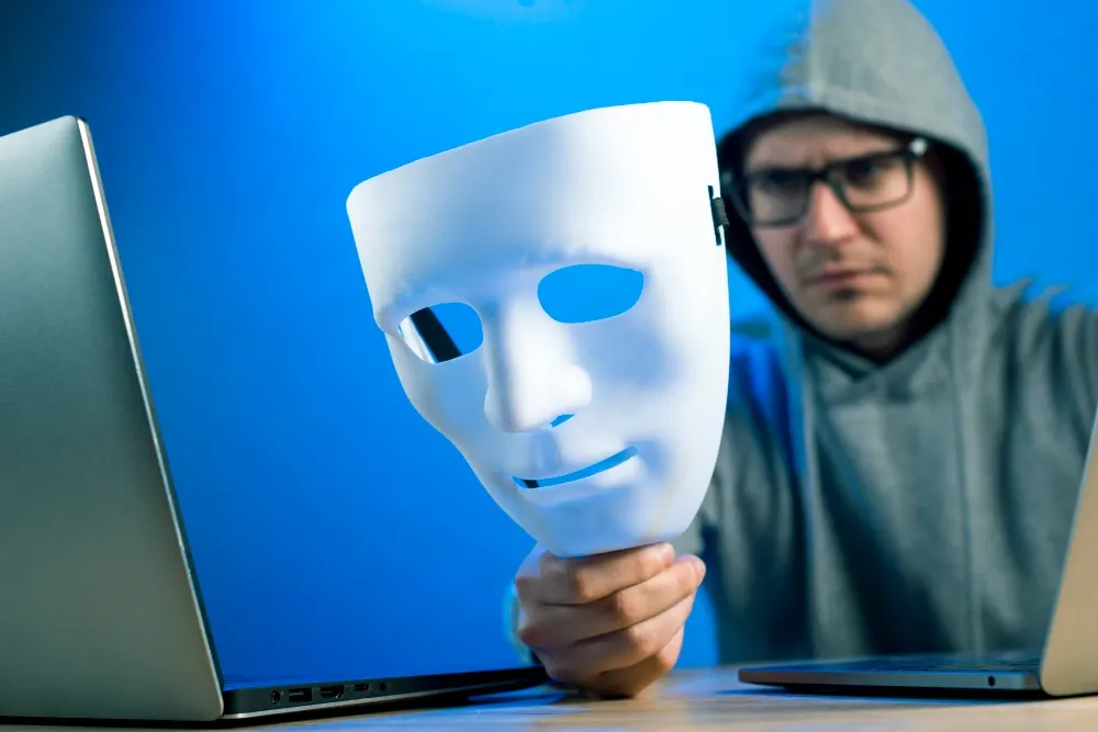 man-holding-a-mask-in-front-of-a-laptop